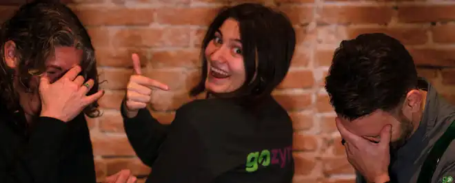 Picture of Heather, Brian and Allen gathered around a table with various laptops and monitors, collaborating in a friendly atmosphere.